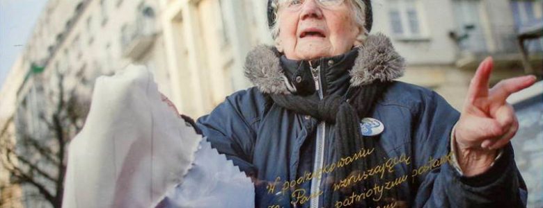 Zdjęcie Starszej Pani z flagą z marszu KOD – „My, Naród”